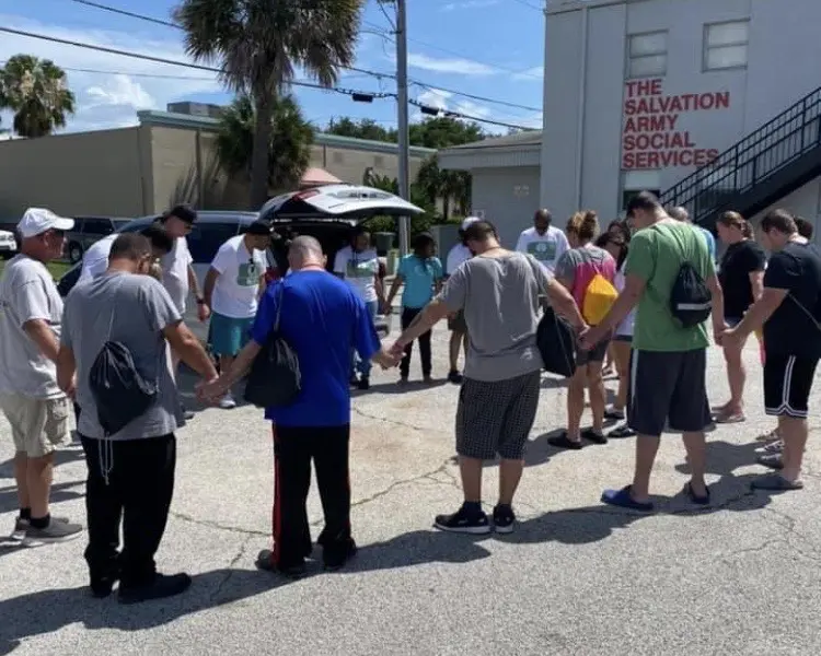 A group of people standing around each other holding hands.