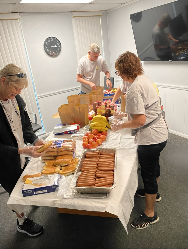 A group of people standing around a table with food.