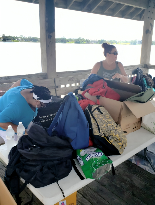 A woman sitting on top of a table next to bags.
