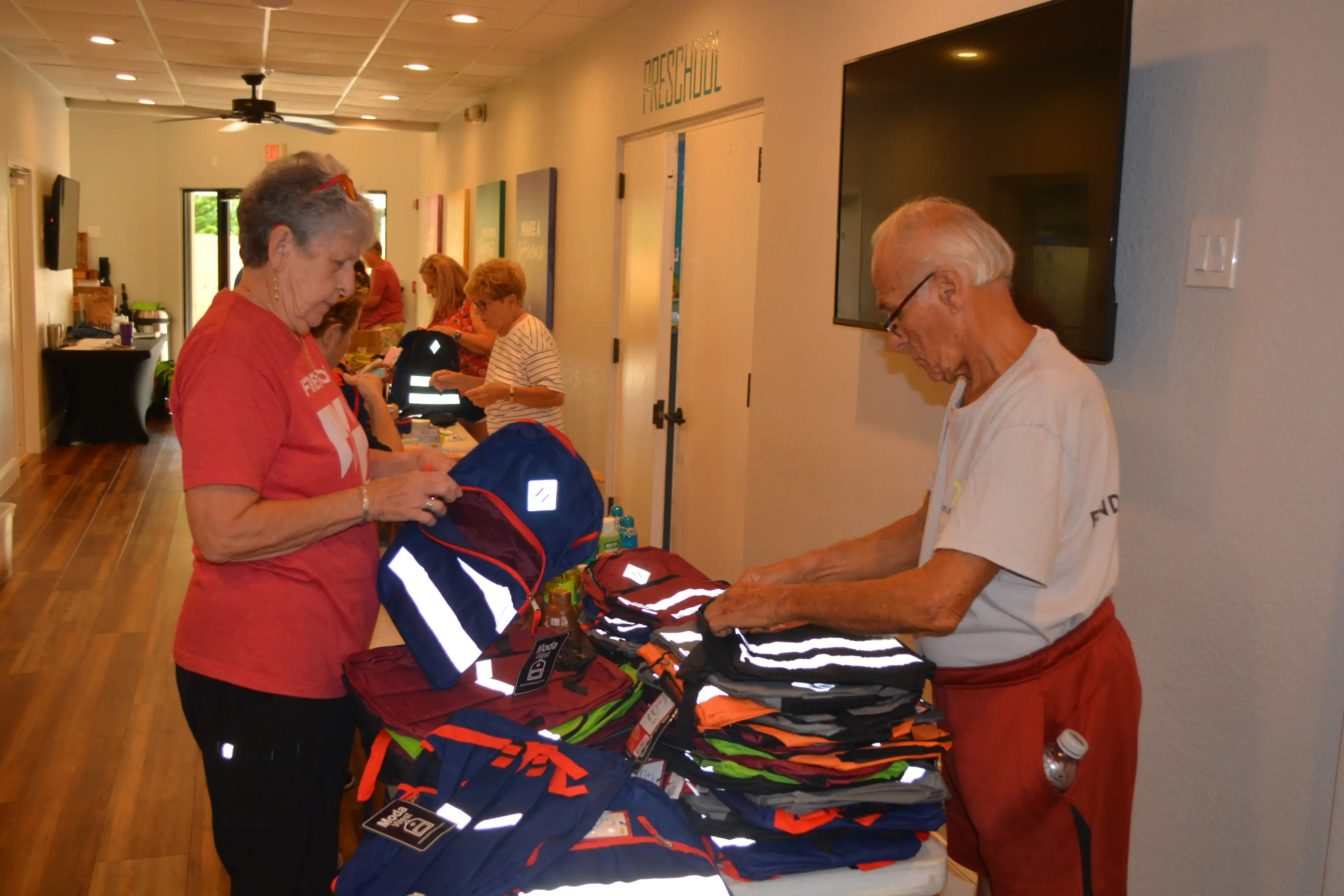 A man and woman sort through clothes at an event.