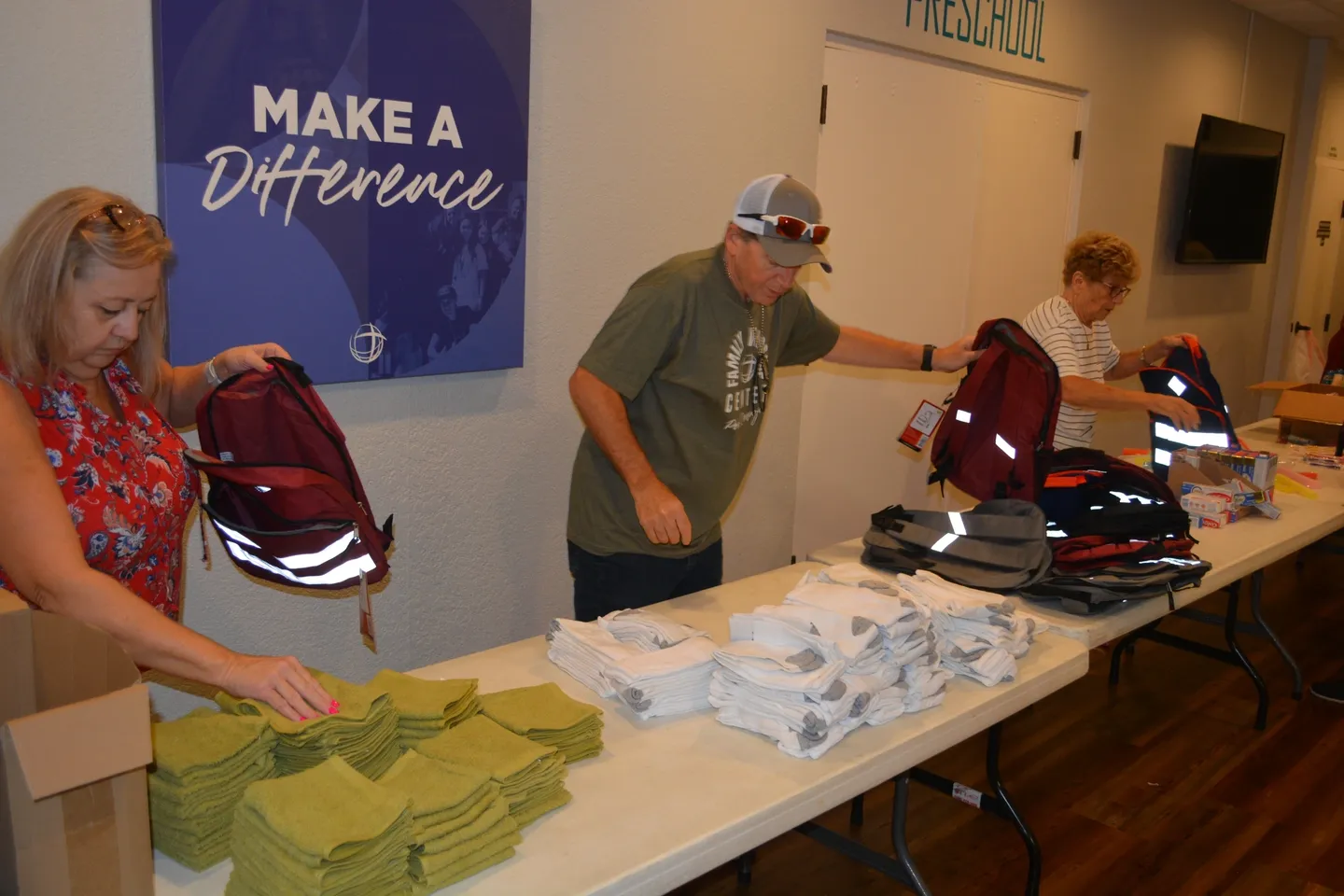A man standing at the table with several bags of supplies.