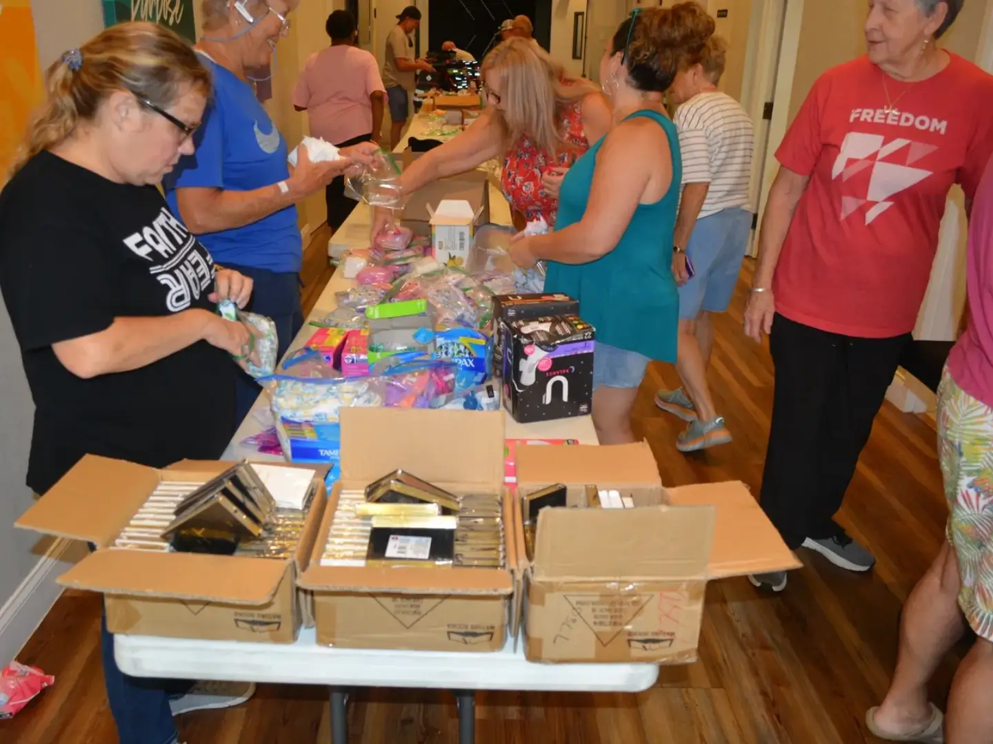 A group of people standing around tables with boxes.